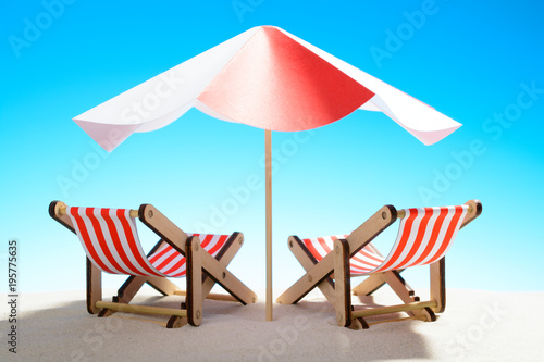 Two chaise longue under an umbrella on the sandy beach  sky with copy space