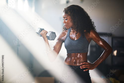 fit african american woman lifting iron in home gym