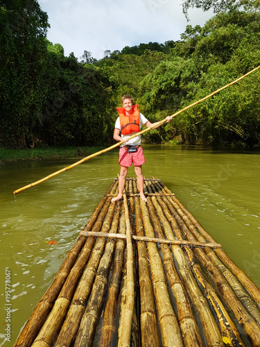 man runs a raft of bamboo on the river