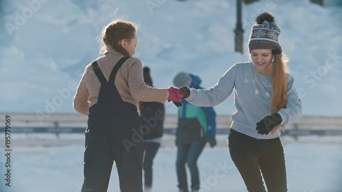 Two teen girlfriends learning to skate and having fun at the rink