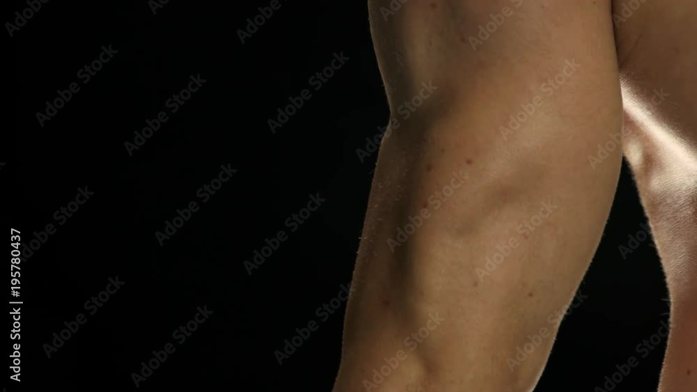 Close up building muscles and strength. Close up man lifting heavy dumbbell. Bodybuilder at work, black background. Close up building muscles and strength. Close up man lifting heavy dumbbell. Bodybuilder at work, black background.