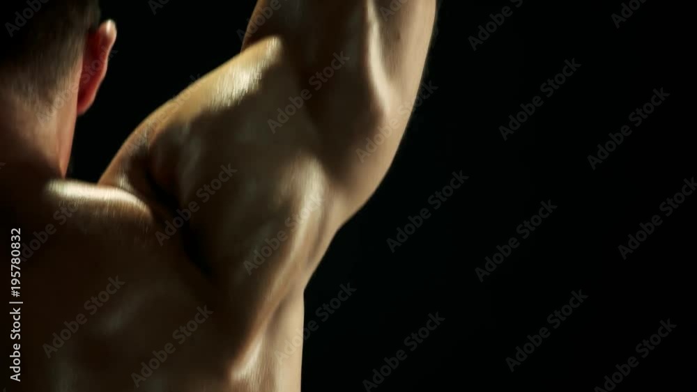 Close up sweaty muscular man training with barbell. Rear view shirtless athletic man working with heavy equipment, dark background. Close up sweaty muscular man training with barbell. Rear view shirtless athletic man working with heavy equipment, dark background.