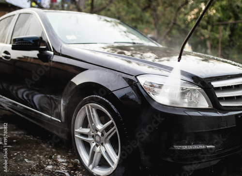 Car wash with pressurized water, car detailing (or valeting) concept. © hedgehog94