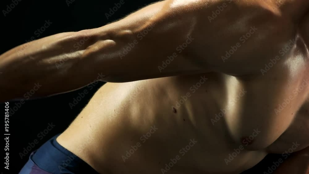 Close up man is exercising with dumbbell. Muscular sweaty man training with dumbbell on black background. Keep shape with sport activity. Close up man is exercising with dumbbell. Muscular sweaty man training with dumbbell on black background. Keep shape with sport activity.