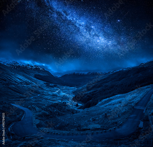 Winding mountain road over a canyon at night with stars