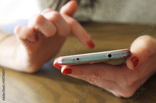 female hands with red manicure holding phone