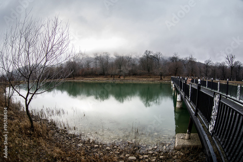 Amazing landscape of bridge reflect on surface water of lake, fog evaporate from pond make romantic scene or Beautiful bridge on lake with trees at fog. © zef art