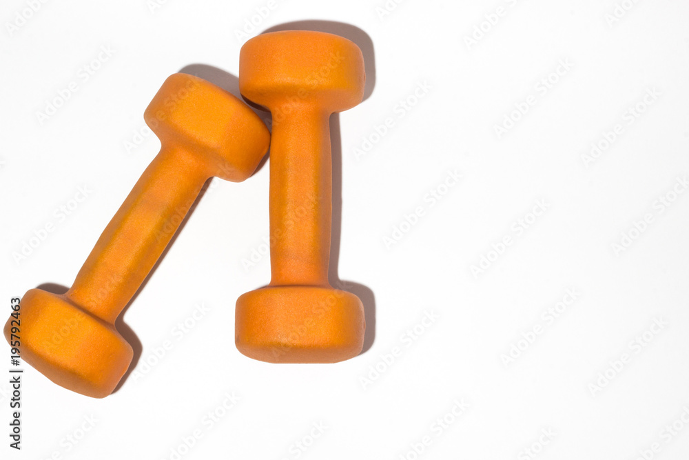 Orange dumbbell on white background close up Orange dumbbell on white background close up