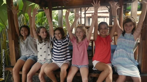 Happy group of young girls waiving their arms in the air sitting together photo