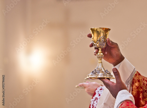 hands of the priest raise the blood of Christ photo