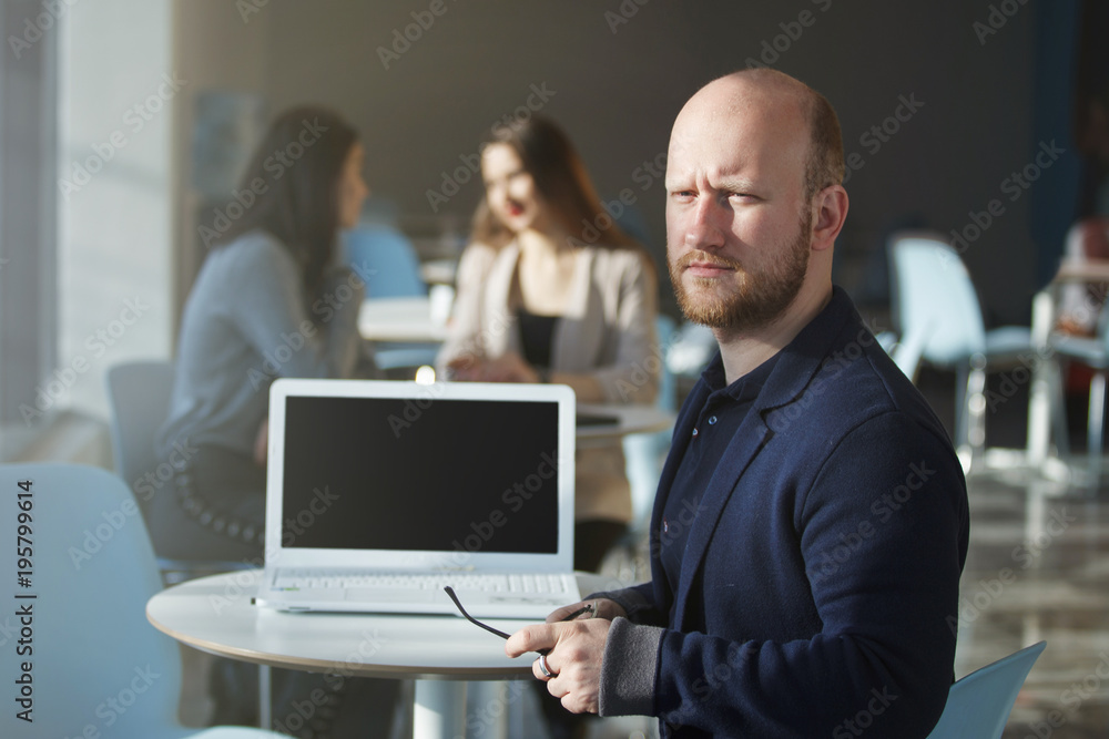Portrait of happy businessman using laptop and colleagues standing behind and discussing in office Portrait of happy businessman using laptop and colleagues standing behind and discussing in office