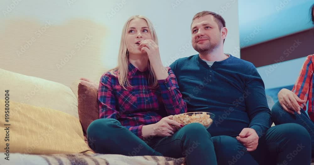 Friends sit on the couch, watch TV, talk, laugh and eat popcorn Friends sit on the couch, watch TV, talk, laugh and eat popcorn