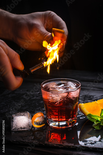 Mezcal Negroni cocktail. Smoky Italian aperitivo. Flamed orange peel.