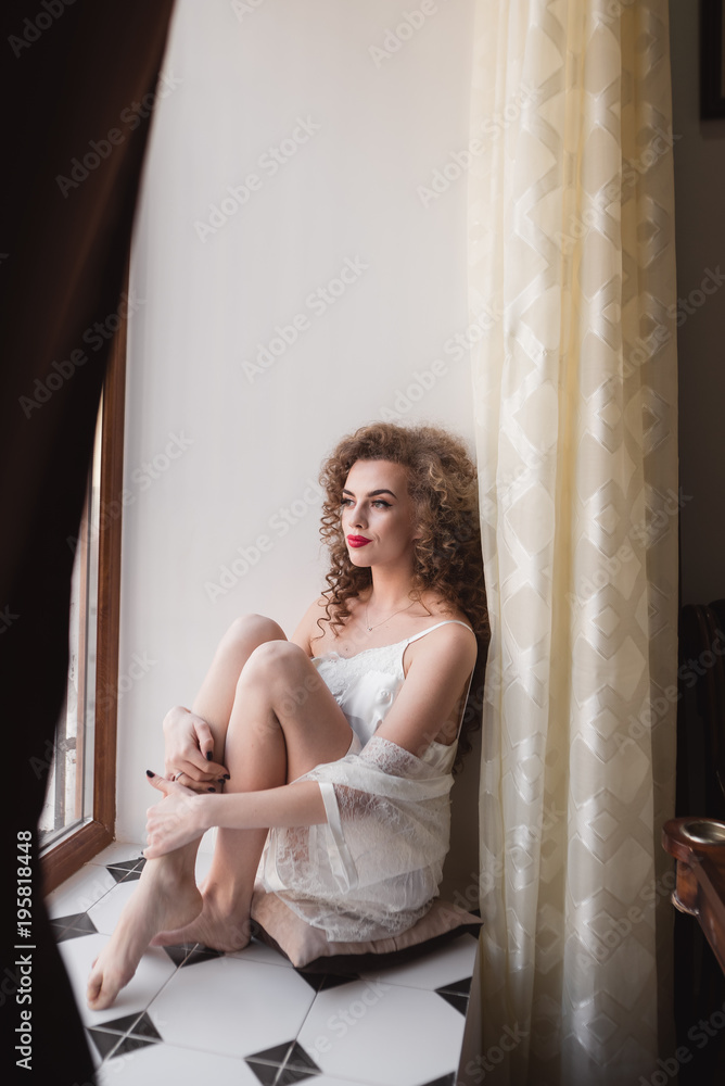 beautiful woman with fresh daily makeup and romantic wavy hairstyle, sitting at the windowsill, draws on glass beautiful woman with fresh daily makeup and romantic wavy hairstyle, sitting at the windowsill, draws on glass