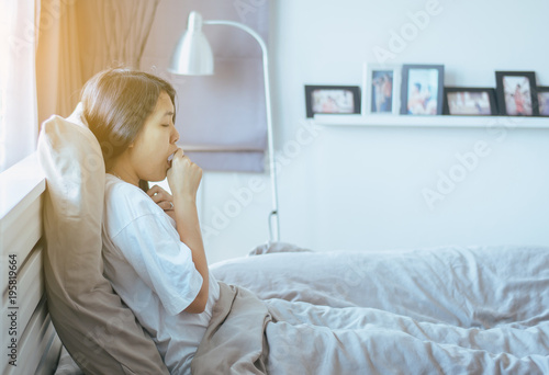 Patient woman coughing and sitting on her bed,Concept of health