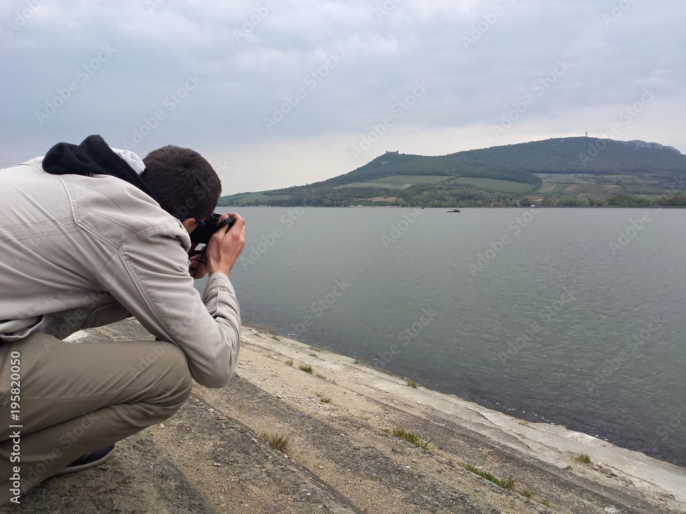 Man taking a photo of Divci hrady in Nove mlyny lake, Moravia Man taking a photo of Divci hrady in Nove mlyny lake, Moravia
