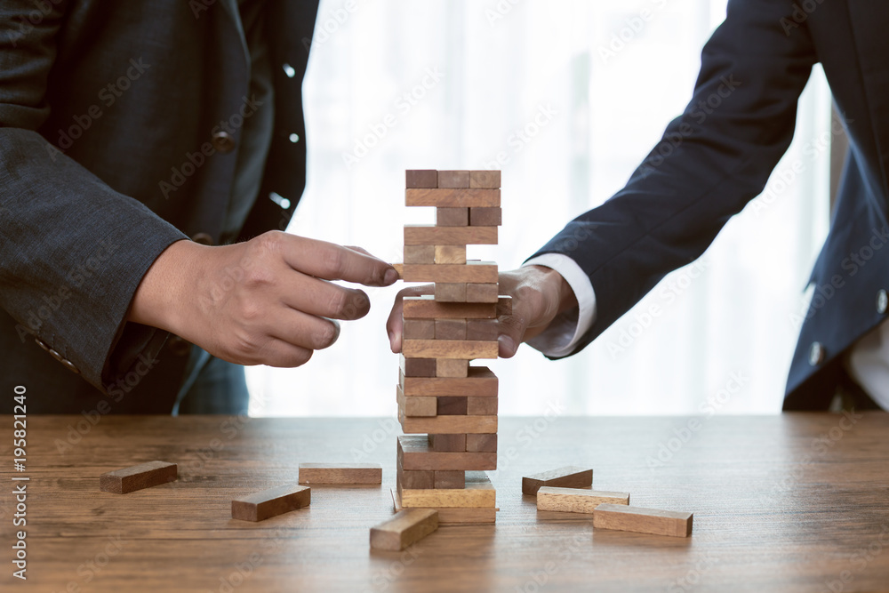 Businessman hands play wood block tower game. Businessman hands play wood block tower game.