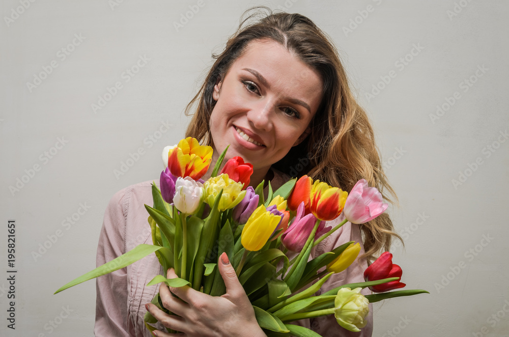 Young charming girl with a bouquet of flowers - multi-colored tulips