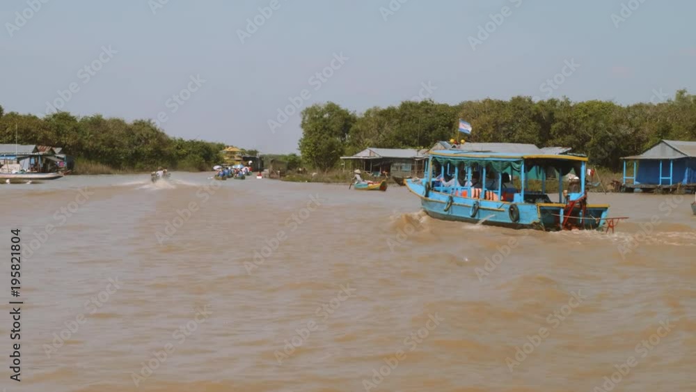 View of houses of floating village and boats with tourists View of houses of floating village and boats with tourists
