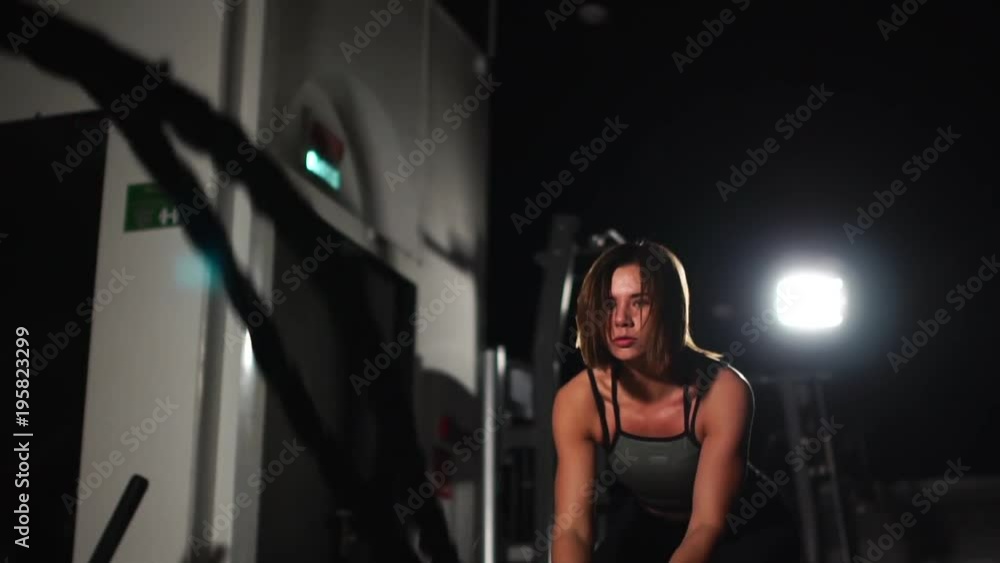 Female athlete working out with heavy ropes at the gym. Female athlete working out with heavy ropes at the gym.