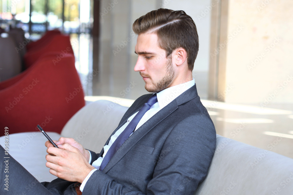 Young businessman sitting relaxed on sofa at hotel lobby making a phone call, waiting for someone. Young businessman sitting relaxed on sofa at hotel lobby making a phone call, waiting for someone.
