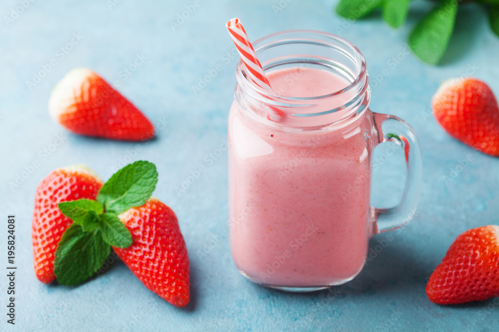 Delicious strawberry smoothie or milkshake in mason jar on turquoise table. Healthy food for breakfast and snack. Delicious strawberry smoothie or milkshake in mason jar on turquoise table. Healthy food for breakfast and snack.