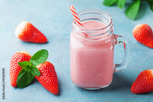 Delicious strawberry smoothie or milkshake in mason jar on turquoise table. Healthy food for breakfast and snack.