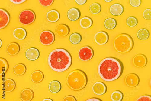 Top view of sliced citrus fruit on yellow background. Flat lay