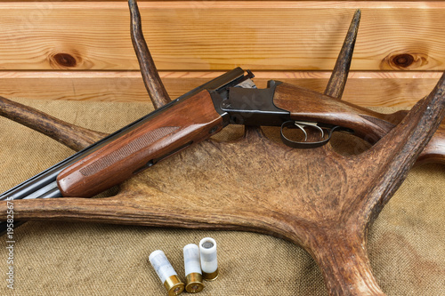 Shotgun on the table with bullets and deer antlers