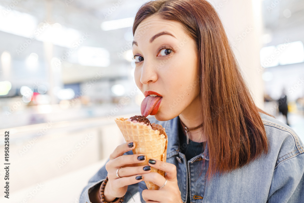 woman eating tasty cone ice-cream in the mall cafe after some shopping woman eating tasty cone ice-cream in the mall cafe after some shopping