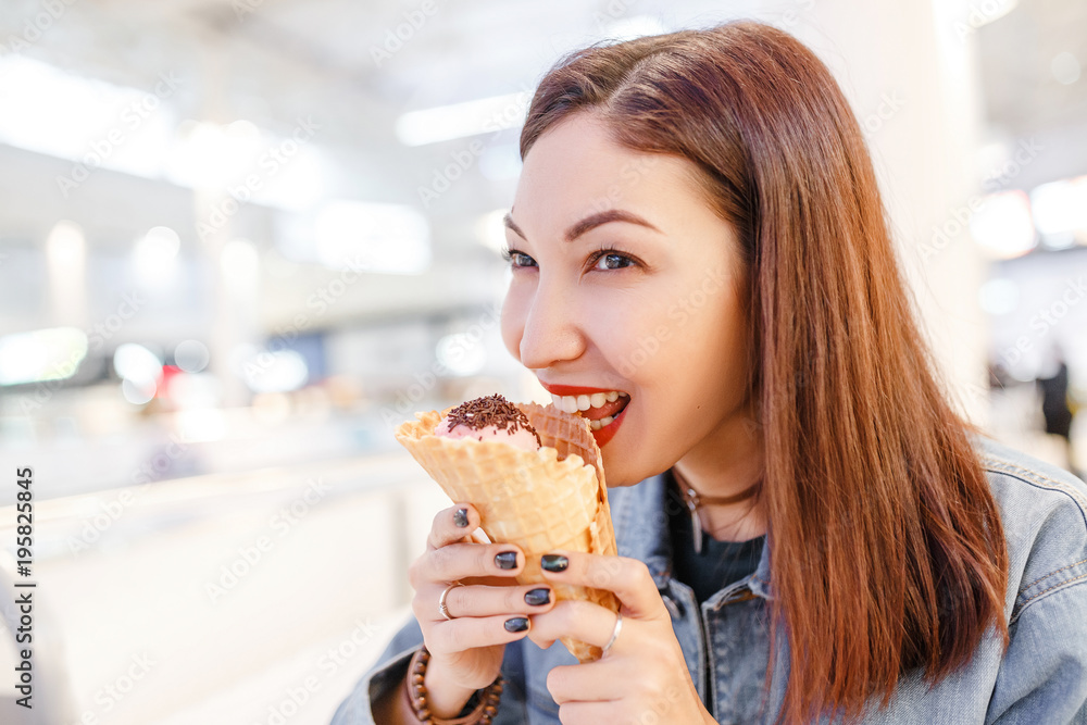 woman eating tasty cone ice-cream in the mall cafe after some shopping woman eating tasty cone ice-cream in the mall cafe after some shopping