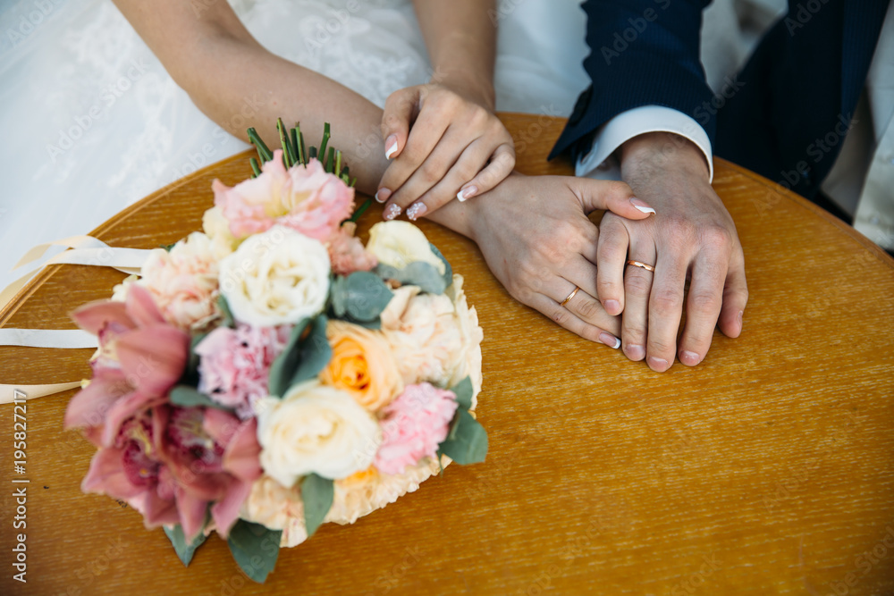 Closeup groom and bride are holding hands at wedding day and show rings. Concept of love family Closeup groom and bride are holding hands at wedding day and show rings. Concept of love family