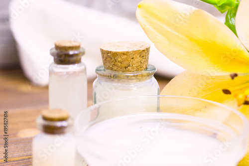 Natural herbal skin care products, top view ingredients coconut, lily flower, essence oil on table concept of the best all natural face moisturizer. Facial treatment preparation background