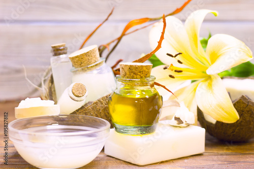 Natural herbal skin care products, top view ingredients coconut, lily flower, essence oil on table concept of the best all natural face moisturizer. Facial treatment preparation background