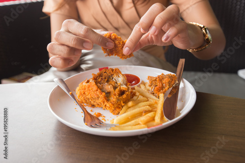 Fried chicken in young woman hand select focus, Hand with fried chicken blur background, Close-up Fried chicken