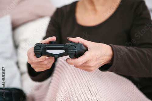 An elderly woman is playing a video game. Elderly person and modern technology.