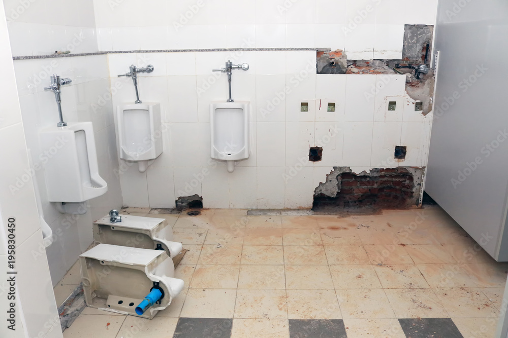 Plumber drilling on the toilet wall for repairing pipeline and