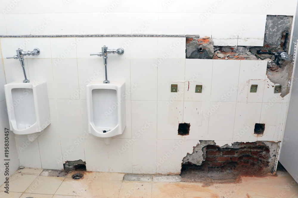 Plumber drilling on the toilet wall for repairing pipeline and