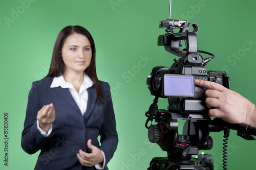 Video recording news in tv studio. Cameraman working on professional digital equipment. TV host looking at the camera