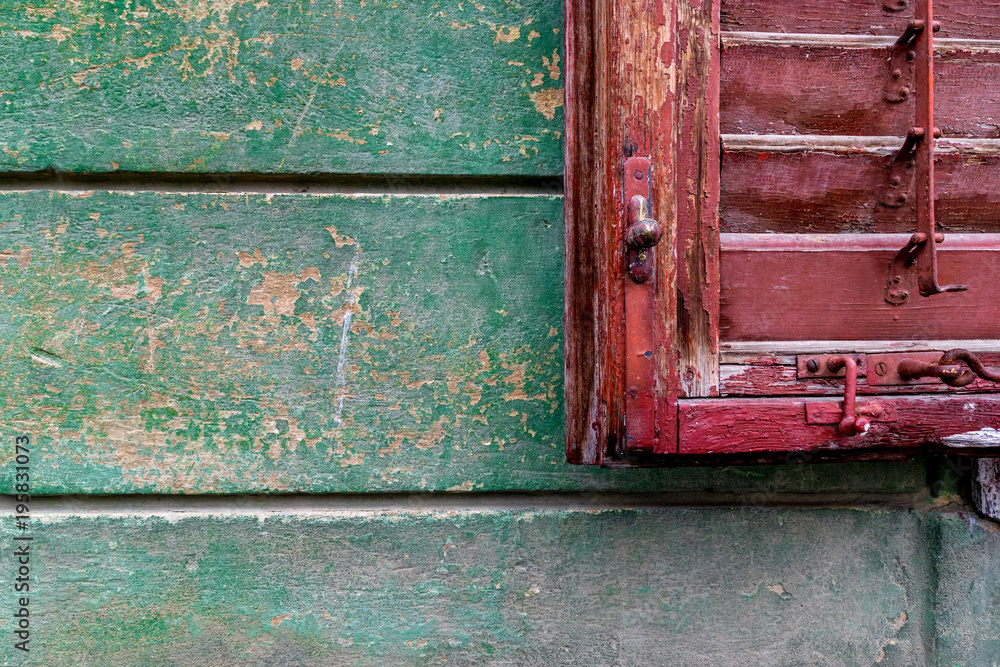 Old red window blind on a green wall Old red window blind on a green wall