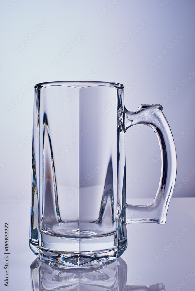 A beautiful transparent glass beer goblet on a light background A beautiful transparent glass beer goblet on a light background