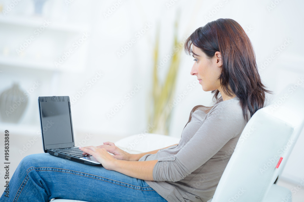 Fototapeta premium woman sat on sofa using laptop
