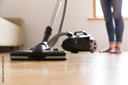 People, housework and housekeeping concept - happy woman with vacuum cleaner at home. Spring cleaning