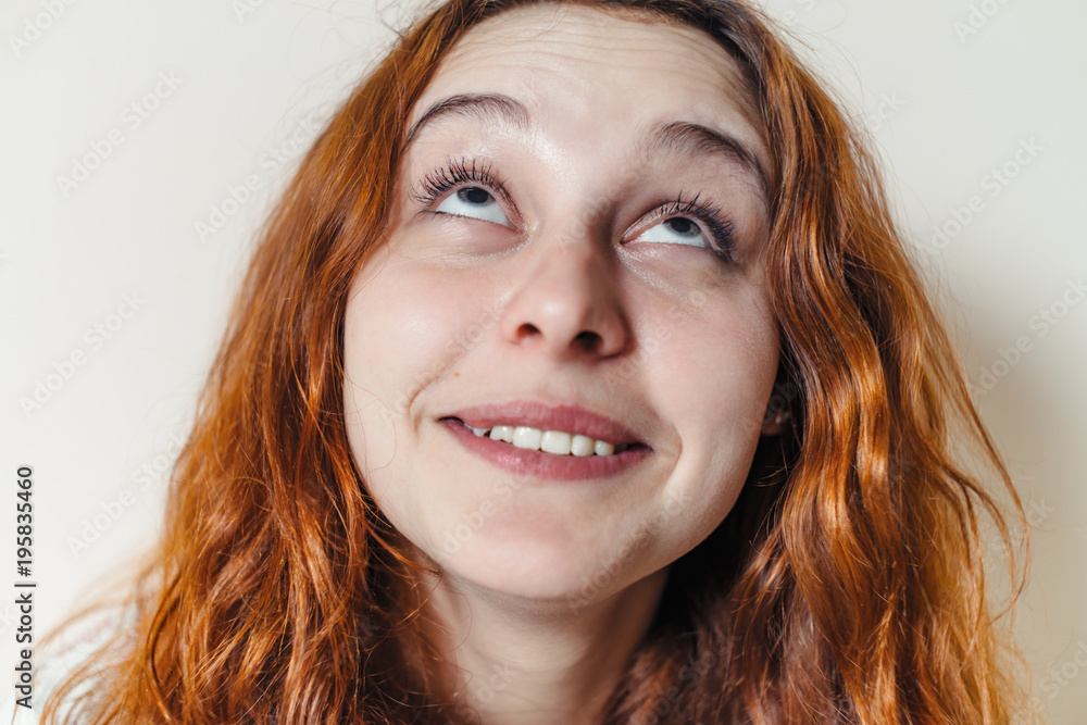Portrait of beautiful cheerful redhead girl with curly hair over beige background. Hair dyed with henna. Professional hair care. Portrait of beautiful cheerful redhead girl with curly hair over beige background. Hair dyed with henna. Professional hair care.