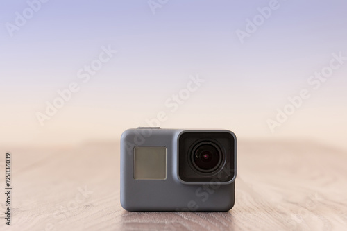 Black 4K action camera on top of a wooden table against a light background