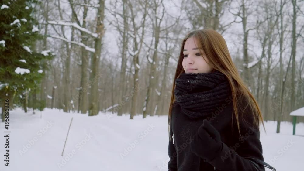 Winter portrait of a young woman. A girl without a headdress walks through the winter park. Winter portrait of a young woman. A girl without a headdress walks through the winter park.