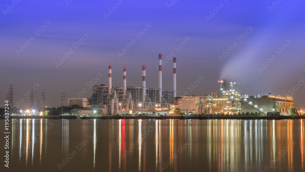 Factory in night time beside big river.