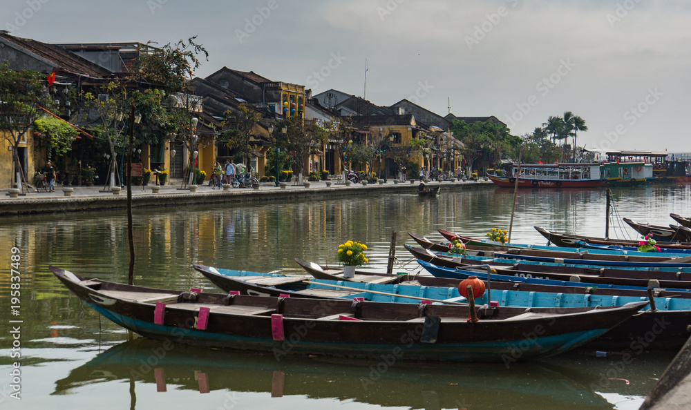 boats with yellow flowers and lanterns tied up along the river in old town of Hoi An, Vietnam