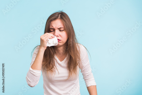 Young woman has a runny nose on blue background