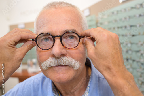 attractive senior man testing new glasses with optician